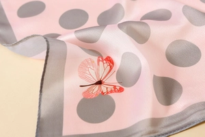 Detail of pink satin scarf showing silk texture with butterfly and polka dot prints