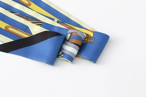 Detail of blue twilly scarf featuring yellow equestrian prints and silk twill texture