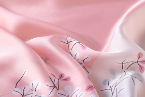 Close-up of pink floral print silk scarf showing soft texture and glossy finish