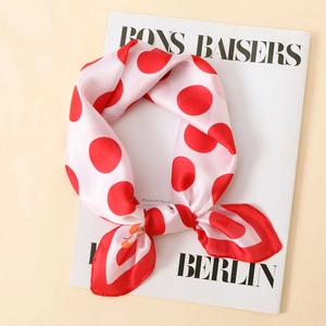 Detail of silk-like satin scarf featuring classic red polka dots on white background