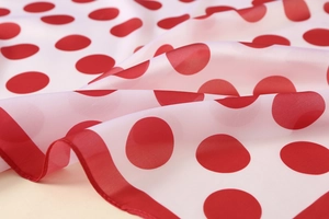 Macro detail of red polka dot satin scarf featuring delicate red stitched edges
