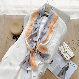 Detail of floral printed silk scarf with pearl accents on a white blazer outfit
