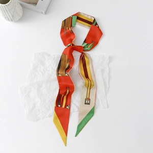 Detail view of red floral silk twilly scarf with equestrian buckle pattern on white paper
