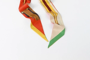 Close-up of long silk-feel scarf featuring colorful equestrian strap print and geometry