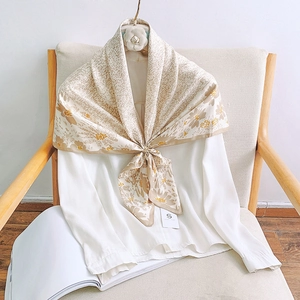 Detailed texture of floral silk scarf draped elegantly over a white shirt on a wooden chair