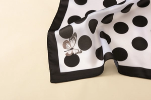 Detailed macro shot of satin scarf featuring black polka dots and butterfly print texture