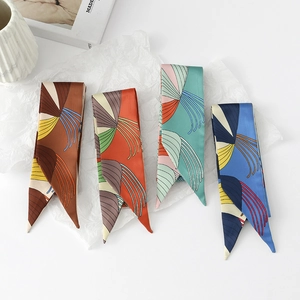 Flat lay of four narrow floral silk-like scarves in brown, orange, green, and blue patterns