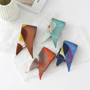Close-up of four colorful skinny silk scarves with abstract patterns on white paper