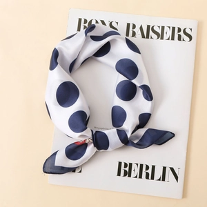 Detail of elegant satin scarf featuring navy blue polka dots on a smooth white fabric