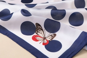 Detail of satin floral scarf showing white base with blue polka dots and a red butterfly