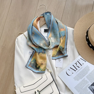 Close-up of ink painting silk scarf draped over a white blazer with a scenery pattern