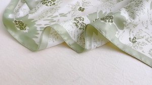 Close-up of floral print silk scarf showing smooth texture and green flower patterns
