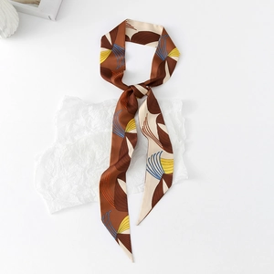 Detailed close-up of brown and beige floral skinny scarf on a textured white background