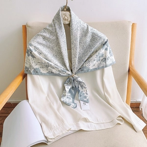 Elegant grey-blue floral faux silk scarf tied on a white shirt in a chic French style