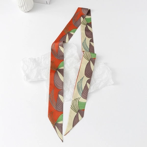 Detailed close-up of a floral silk twilly scarf with vibrant orange and green patterns