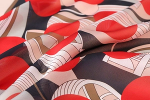 Macro shot of satin scarf featuring geometric red circles and beige striped patterns