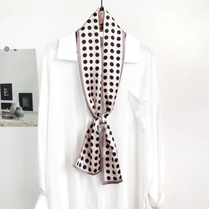 Close-up of elegant pink silk scarf with black polka dots tied on a white shirt collar