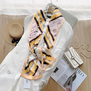 Detail of luxury satin scarf with equestrian patterns styled on a white blazer