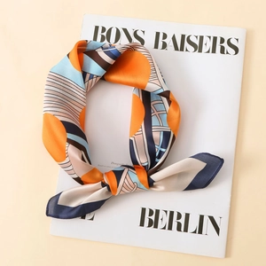 Detail view of smooth satin scarf texture with orange and blue geometric patterns