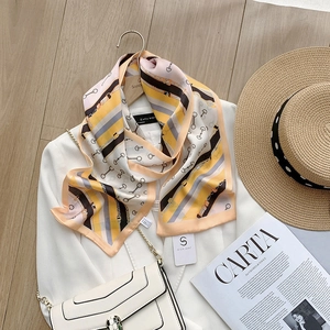 Detail of silk-like scarf with yellow stripes and horsebit chain print pattern