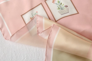 Detailed view of pink satin scarf with floral illustration and rolled hem edges