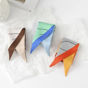 Detailed view of three colorful geometric print narrow silk scarves on white paper