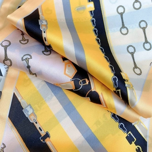 Detail of silk scarf with equestrian horse bit print and vibrant yellow chain pattern