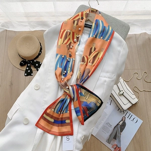 Detail of silk-feel scarf with orange ink painting print and delicate pearl accents