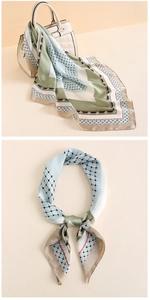 Dettaglio di un foulard in raso a blocchi di colore annodato su un manico di borsa in pelle