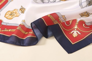 Close-up of printed satin scarf showing crown motifs and silky smooth texture detail