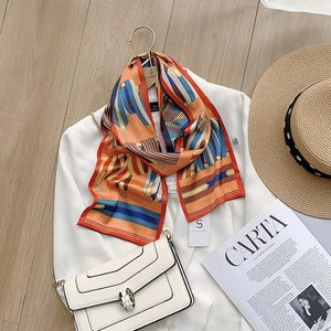 Detail of equestrian silk scarf with horse stirrup prints styled on a white blazer