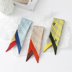 Detailed view of floral skinny silk scarves with geometric chain patterns and pointed ends
