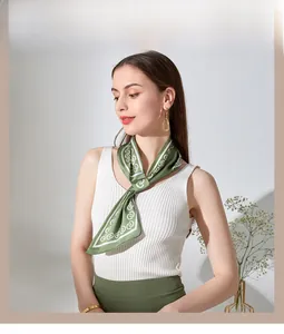 Dettaglio di un foulard in seta verde bosco annodato al collo con motivi geometrici bianchi