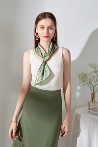 Dettaglio foulard di seta verde a fiori annodato al collo con gilet bianco e gioielli