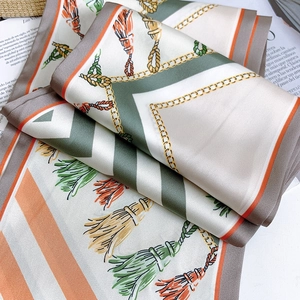 Detailed macro view of the elegant satin scarf featuring vintage chain and tassel patterns
