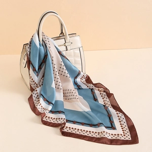 Elegante sciarpa in raso con stampa geometrica blu e beige su una borsa a mano bianca