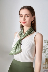 Dettaglio del foulard in finta seta verde scuro con motivi floreali e geometrici bianchi
