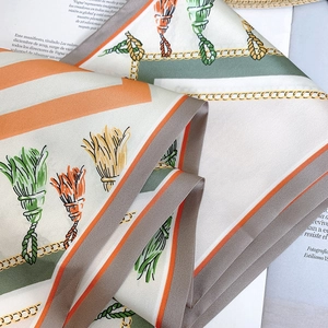 Detail view of silk scarf with orange tassels and gold chains on a magazine