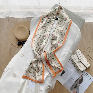 Detail of floral silk scarf with elegant pearl accents and vibrant orange borders