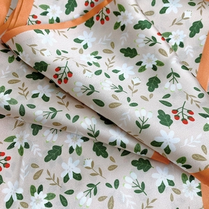 Detailed close-up of floral print silk scarf featuring elegant orange rolled edges