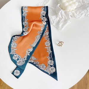 Elegante sciarpa di seta floreale arancione e blu con finitura satinata su tavolo bianco