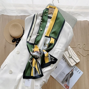Close-up of silk scarf with green and yellow geometric zebra print on white blazer