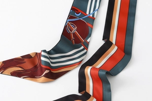Detailed view of the equestrian print and smooth texture on this slim floral silk scarf