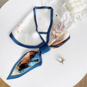 Dettaglio di foulard in seta con stampa di fiori e uccelli e accessori ad anello dorati