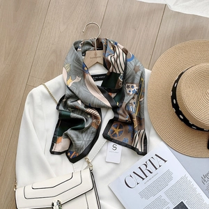 Detail of silk scarf with geometric star print draped on a hanger with a white blazer