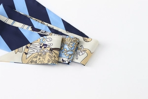 Close-up of floral silk twilly scarf with blue diagonal stripes and artistic illustration