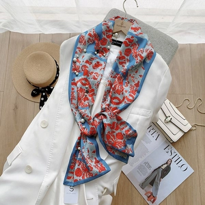Detailed close-up of dark blue silk scarf with floral patterns, pearls, and bead accents
