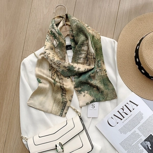 Detail view of a long silk scarf featuring green architectural prints and refined texture