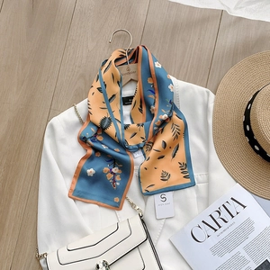 Detailed macro view of the floral print and smooth silk-like texture of the long scarf