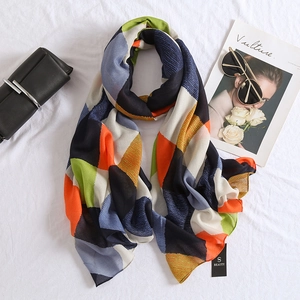 Flat lay of colorful geometric pattern scarf with stylish sunglasses and fashion magazine